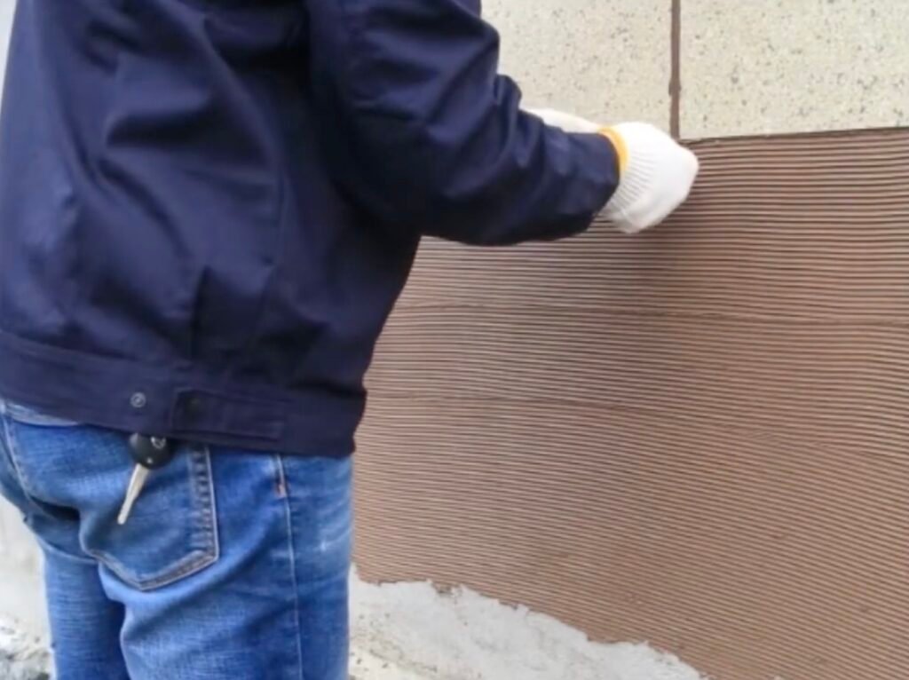 Worker applying lightweight flexible stone veneer to curved wall