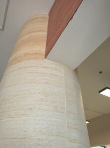 nterior designer demonstrating flexible stone panels bending around curved surfaces versus ceramic tile limitations