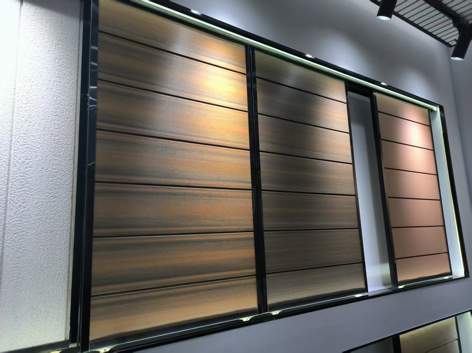 Paneles de pared WPC mostrados con diferentes acabados y perfiles en una exhibición de sala de muestra, ya que el peso varía según el perfil y la formulación